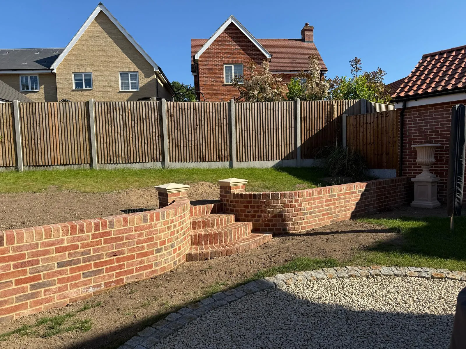Curved brick retaining wall and steps in a landscaped garden