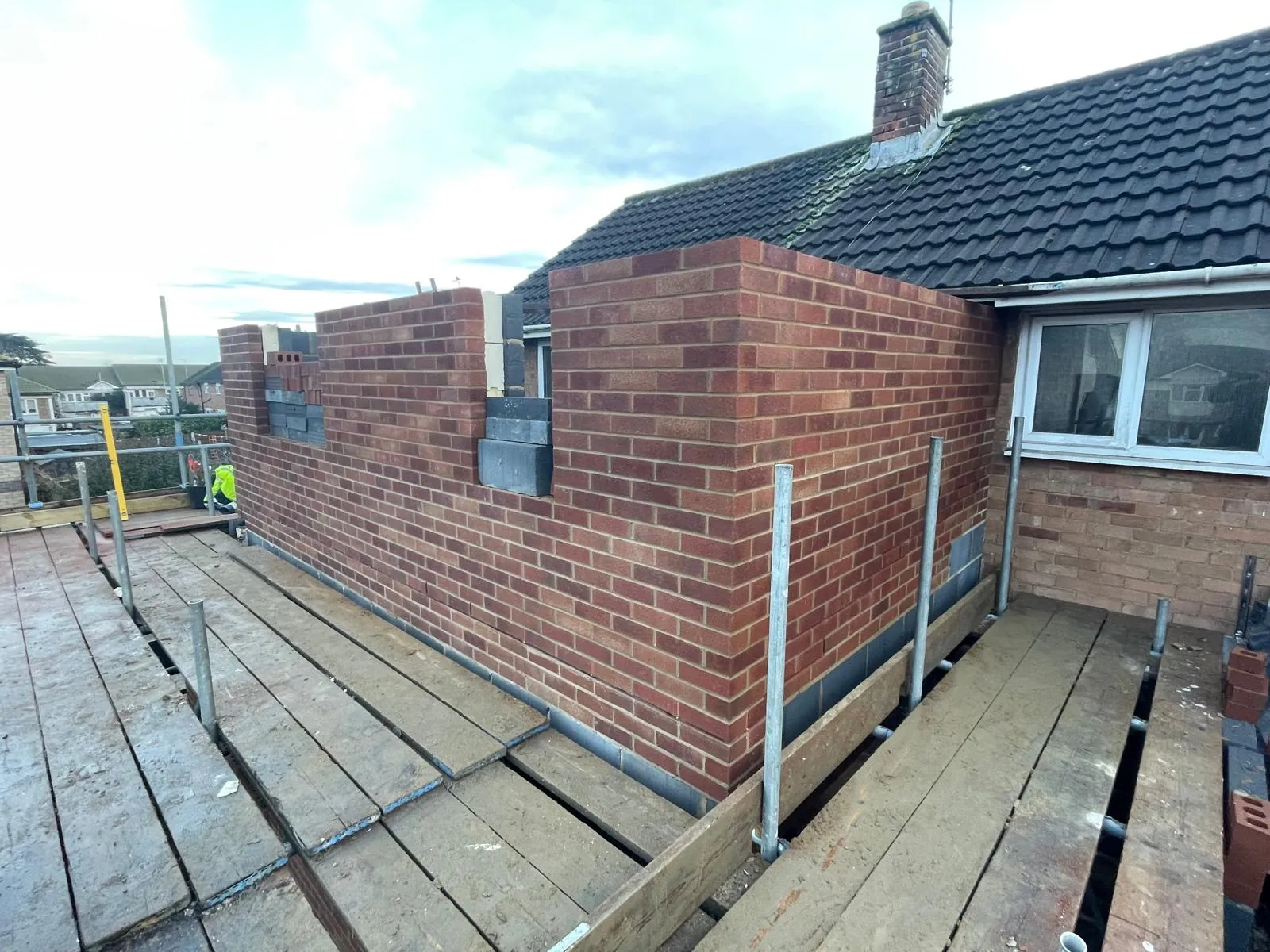 Extension brickwork rising past the scaffold on a bungalow
