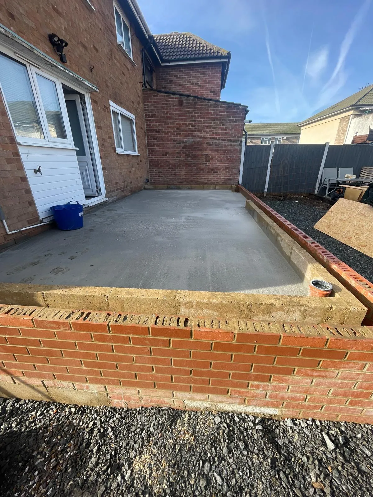 Freshly poured concrete slab inside new brick edging